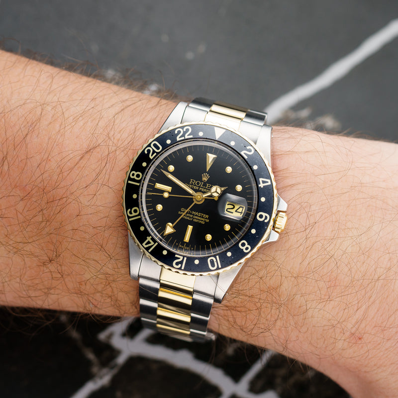 Front view of a Rolex GMT Master 1675 featuring a stainless steel and yellow gold case, 40mm size, with a black dial and iconic rotating bezel.