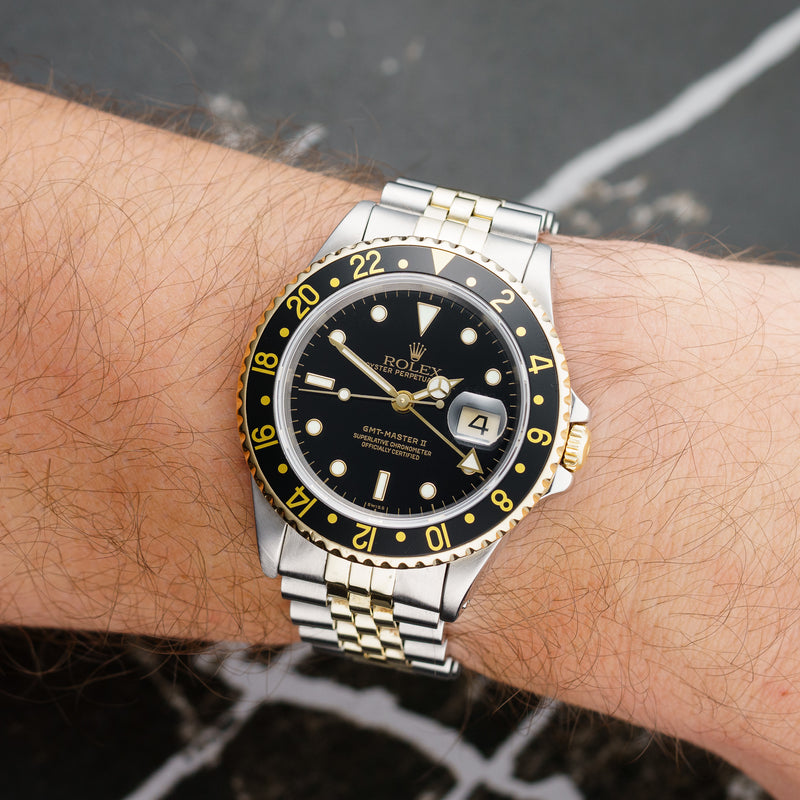 Front view of a Rolex GMT Master II 16713 featuring a stainless steel and yellow gold case, 40mm size, with a black bezel and a two-tone bracelet.