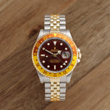 Front view of a Rolex GMT Master II 16713 featuring a stainless steel and yellow gold case, 40mm size, with a black dial and gold hour markers.