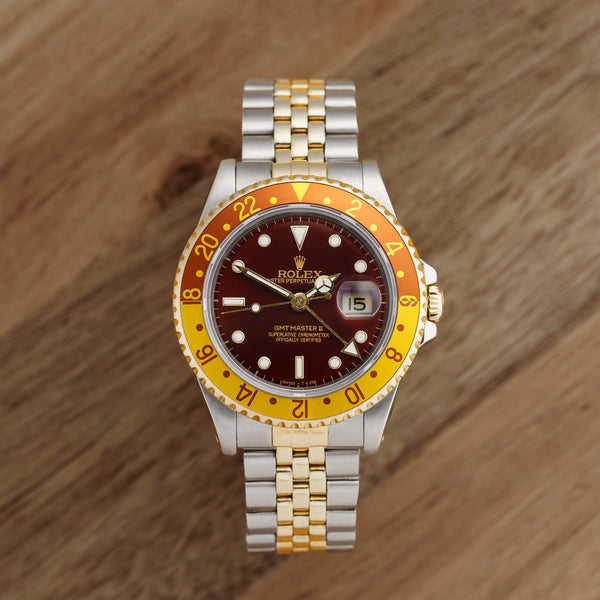 Front view of a Rolex GMT Master II 16713 featuring a stainless steel and yellow gold case, 40mm size, with a black dial and gold hour markers.
